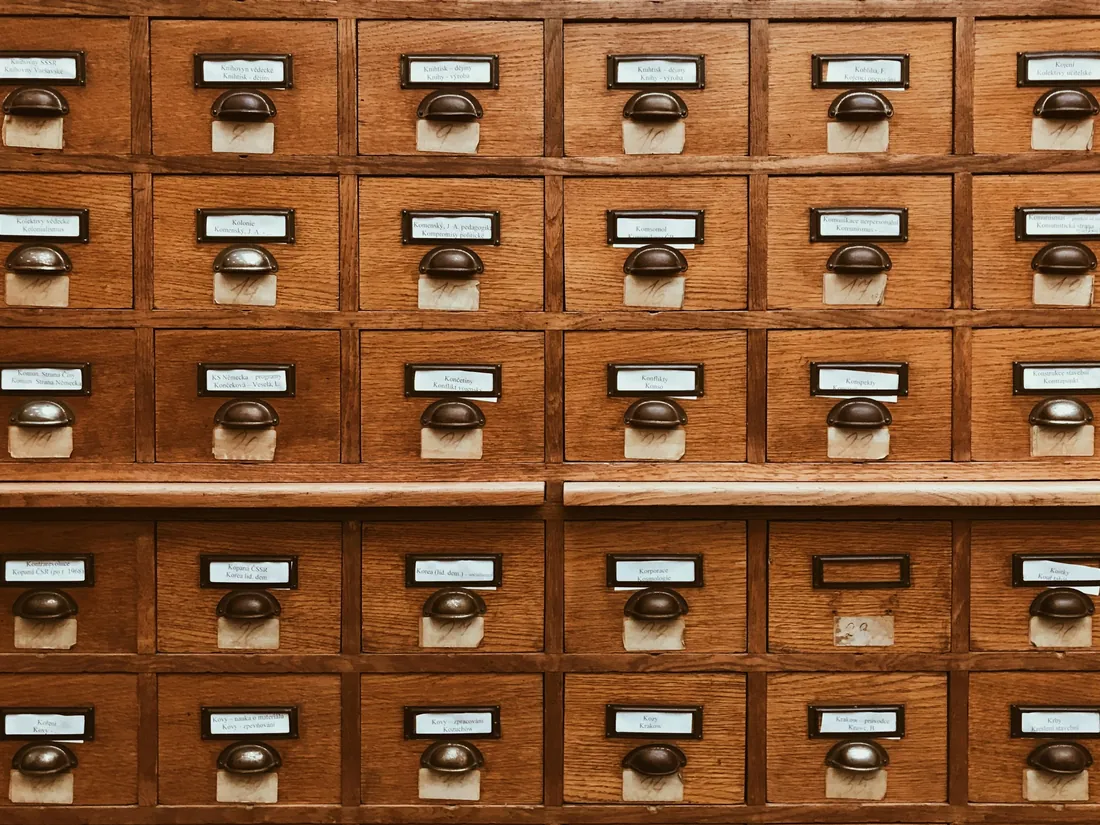 A wall of wooden card-index drawers with brass label holders.