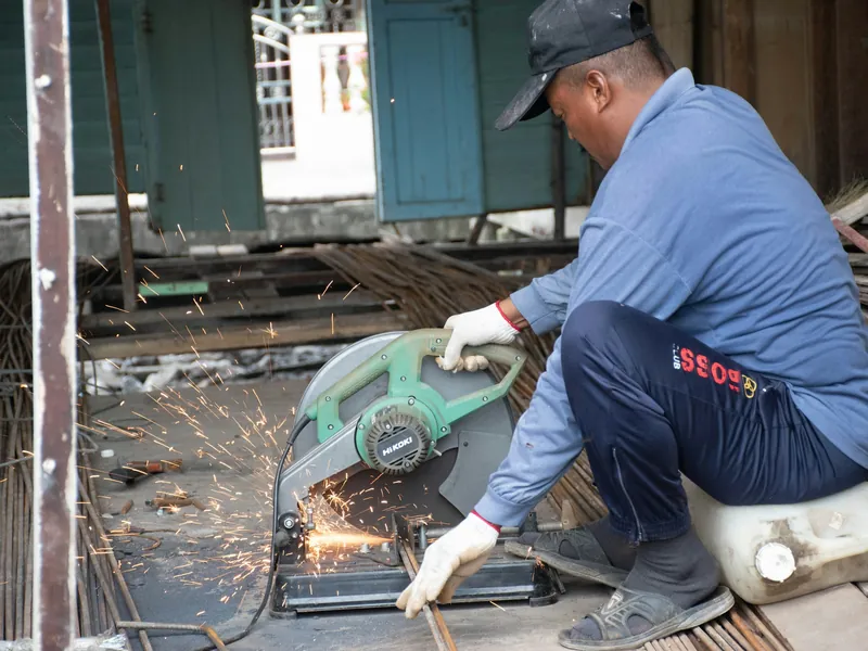 A fabricator cutting steel with an angle grinder, sparks flying.
