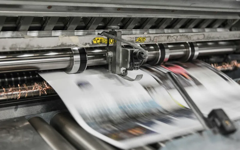 Printed sheets moving through a press.